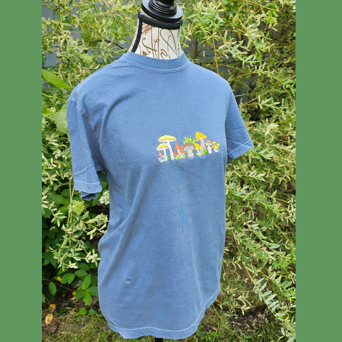 blue t shirt with mushrooms embroidered on it